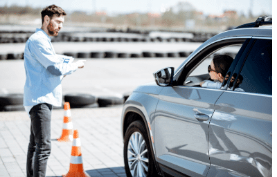 Lehrer steht neben Fahrzeug beim Fahrsicherheitstraining