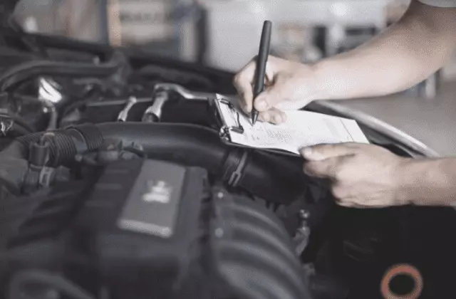 Ein Formular wird in der Motorhaube eines Pkw ausgefüllt